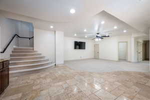 Unfurnished living room with a ceiling fan, recessed lighting, stone tile flooring, and stairway