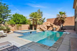 View of swimming pool featuring a patio area, a fenced backyard, and a pool with connected hot tub