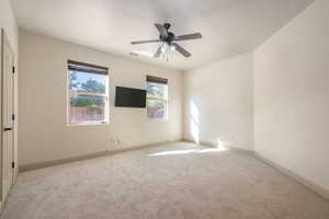 Carpeted spare room featuring a ceiling fan and baseboards