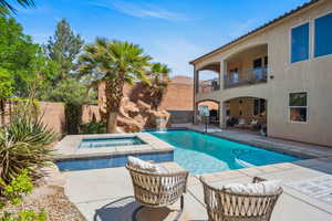 View of swimming pool featuring a patio, a balcony, a fenced backyard, and a pool with connected hot tub