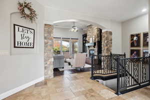 Hall with stone tile flooring, crown molding, an upstairs landing, and arched walkways