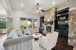 Living area with ornamental molding, a fireplace, a ceiling fan, wood finished floors, and recessed lighting