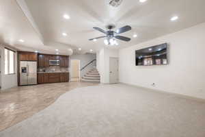 Unfurnished living room with recessed lighting, ceiling fan, stone tile flooring, stairway, and light colored carpet