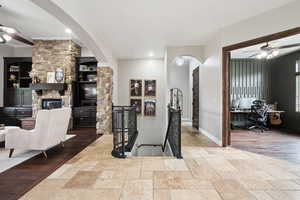 Dining space featuring ceiling fan, a desk, stone tile flooring, and arched walkways