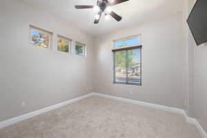 Carpeted spare room featuring baseboards and ceiling fan