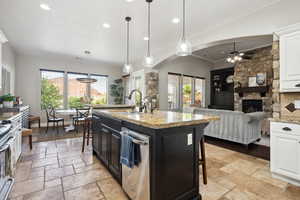 Kitchen with a kitchen breakfast bar, pendant lighting, dark cabinetry, a center island with sink, and appliances with stainless steel finishes