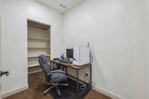 Home office featuring dark colored carpet and built in features