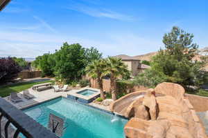 View of pool featuring a patio, a fenced backyard, and a pool with connected hot tub