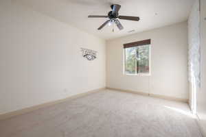Carpeted empty room featuring baseboards and ceiling fan