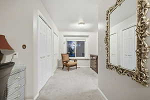 Hall with light colored carpet and baseboards