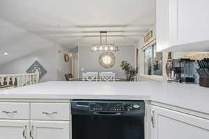 Kitchen with white cabinets, light countertops, black dishwasher, and a peninsula