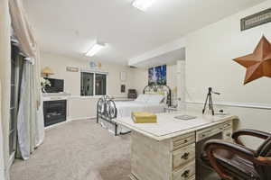 Bedroom with light colored carpet and a fireplace