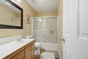 Full bath featuring bath / shower combo with glass door, vanity, and light tile patterned floors