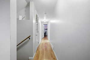 Hallway with light wood finished floors and an upstairs landing