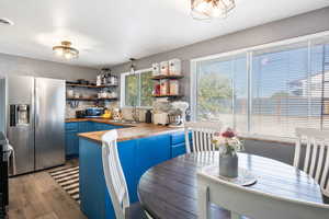 Kitchen featuring butcher block countertops, blue cabinetry, stainless steel appliances, hanging light fixtures, and a peninsula