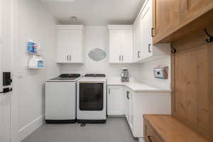 Laundry area with separate washer and dryer, cabinet space, and light tile patterned floors