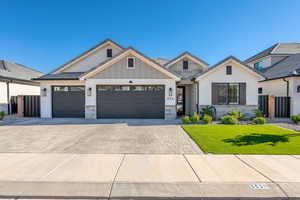 Modern farmhouse featuring decorative driveway, stone siding, an attached garage, and board and batten siding