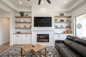Living area featuring a fireplace, ceiling fan, light wood-style floors, and recessed lighting