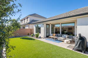 Rear view of house featuring stucco siding, an outdoor living space, and a patio area
