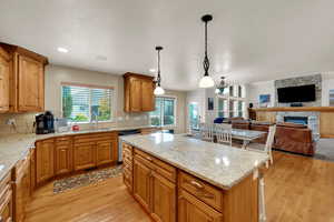 Kitchen featuring light stone counters, tasteful backsplash, open floor plan, light wood-style floors, and recessed lighting