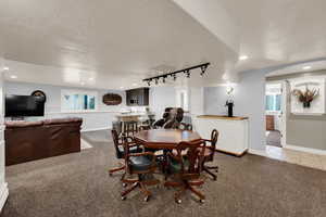 Dining area with track lighting, light colored carpet, a textured ceiling, recessed lighting, and arched walkways