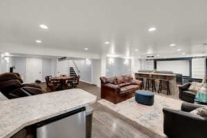 Living area with recessed lighting, stairway, bar, crown molding, and light wood-style flooring