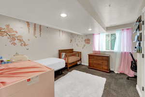 Bedroom with dark carpet, a textured ceiling, and wallpapered walls