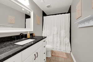 Full bathroom featuring vanity, a textured ceiling, light tile patterned flooring, and shower / tub combo