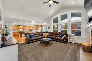 Living room with high vaulted ceiling, recessed lighting, ceiling fan, a fireplace, and light wood-style floors