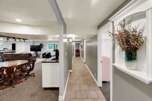Corridor featuring light colored carpet, light tile patterned floors, a textured ceiling, rail lighting, and recessed lighting