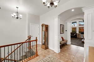 Corridor with a chandelier, arched walkways, vaulted ceiling, light tile patterned flooring, and recessed lighting