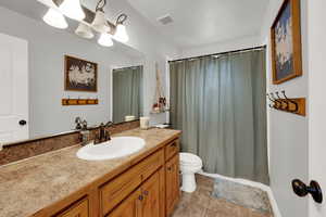 Full bath with vanity, a shower with shower curtain, and light tile patterned flooring