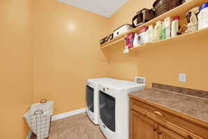 Washroom featuring light tile patterned floors, washer and dryer, and cabinet space