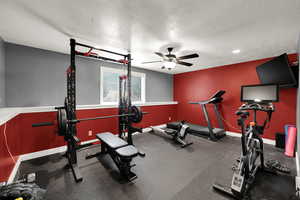 Workout area with a textured ceiling, rubber floors, and ceiling fan