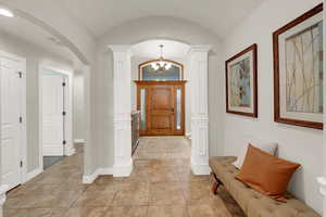 Foyer with a chandelier, light tile patterned floors, arched walkways, and lofted ceiling