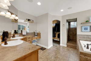 Bathroom with vanity, a garden tub, a walk in closet, light tile patterned flooring, and recessed lighting