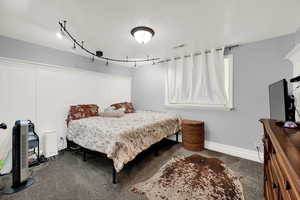 Bedroom featuring carpet, track lighting, and a textured ceiling