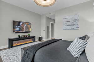 Bedroom with a glass covered fireplace and wood finished floors