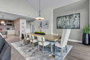 Dining area with light wood finished floors and high vaulted ceiling