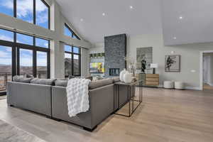 Living room featuring a fireplace, a high ceiling, light wood finished floors, and recessed lighting
