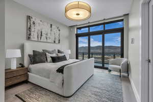 Bedroom featuring a wall of windows, access to exterior, a mountain view, and wood finished floors