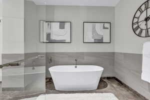 Bathroom with a soaking tub, tile walls, and wainscoting