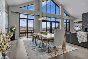 Dining space with high vaulted ceiling, healthy amount of natural light, a fireplace, and light wood-style floors