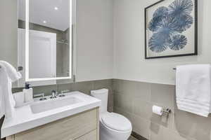 Bathroom featuring tile walls, vanity, a shower, and recessed lighting