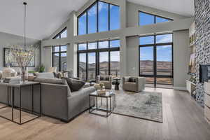 Living area featuring high vaulted ceiling, a stone fireplace, and light wood-style floors