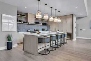 Kitchen featuring light brown cabinets, modern cabinets, a kitchen breakfast bar, tasteful backsplash, and open shelves