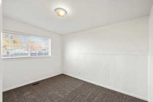 Empty room with wainscoting and dark colored carpet