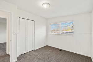 Unfurnished bedroom featuring dark carpet and a closet