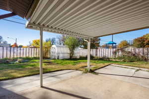 Fenced backyard featuring an outbuilding and a patio