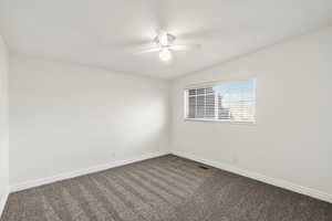 Carpeted spare room featuring baseboards and ceiling fan